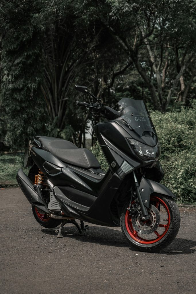 Stylish black Yamaha scooter parked on forest path, perfect for adventure enthusiasts.